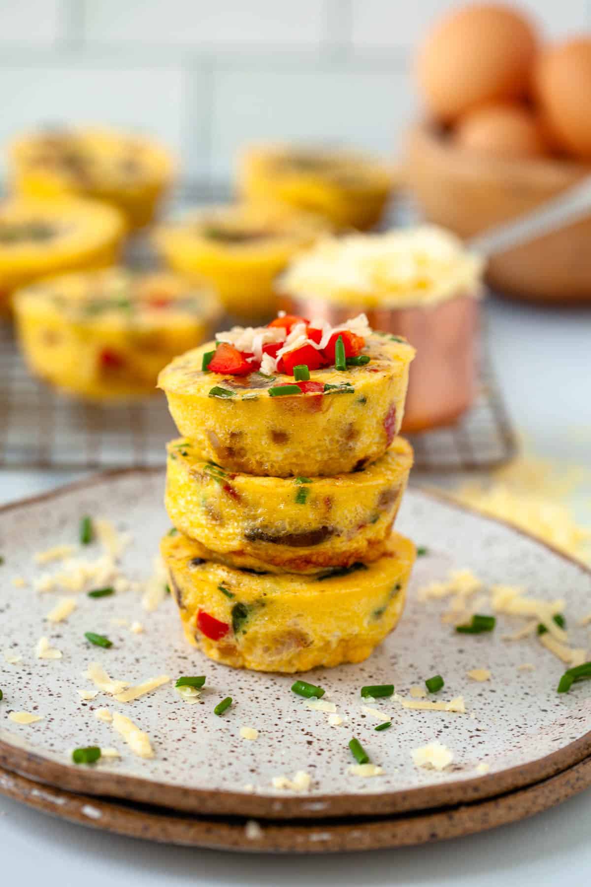 3 egg bites. stackled on speckled plate. extra egg bites. blurred in background. 