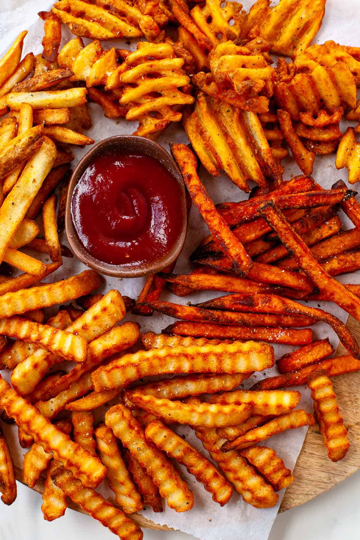 frozen fries sweet potato, crinkle cut, waffle and steak with small bowl of ketchup